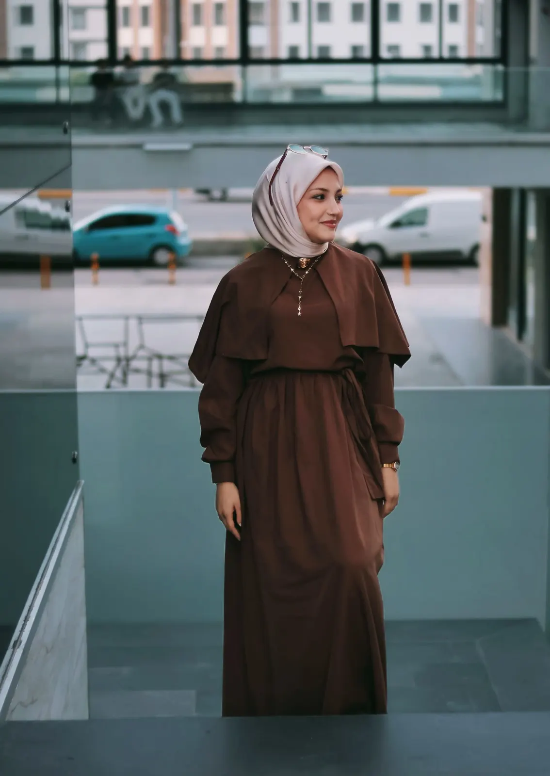 Long cocoa dress and blush hijab in a modern courtyard